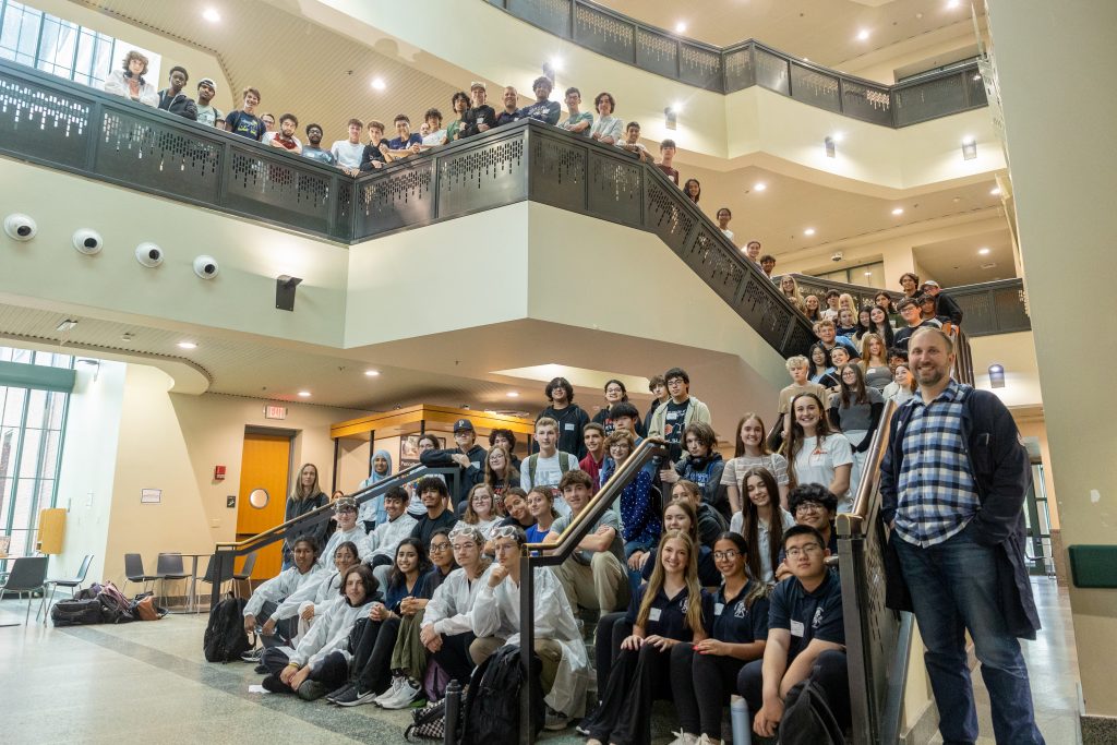 Over 100 high school students who attended the Early College Experience Chemistry Student Lab Day pose for a photo with Dr. Michael Kienzler, assistant professor of chemistry at UConn